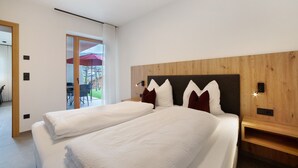 Une chambre d’hôtel moderne avec un grand lit, une tête de lit en bois et une vue sur l’espace extérieur.