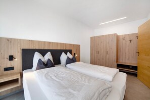 Ein modernes Schlafzimmer mit Bett, Nachttisch, Holzschrank und integrierter Beleuchtung.