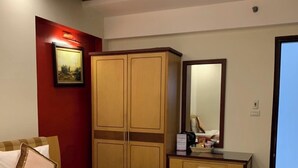 A hotel room with a large bed, a wooden wardrobe, a desk with a mirror, and a red accent wall. - Love Hotel Hoang Mai HN- by Bay Luxury (Hanoi)
