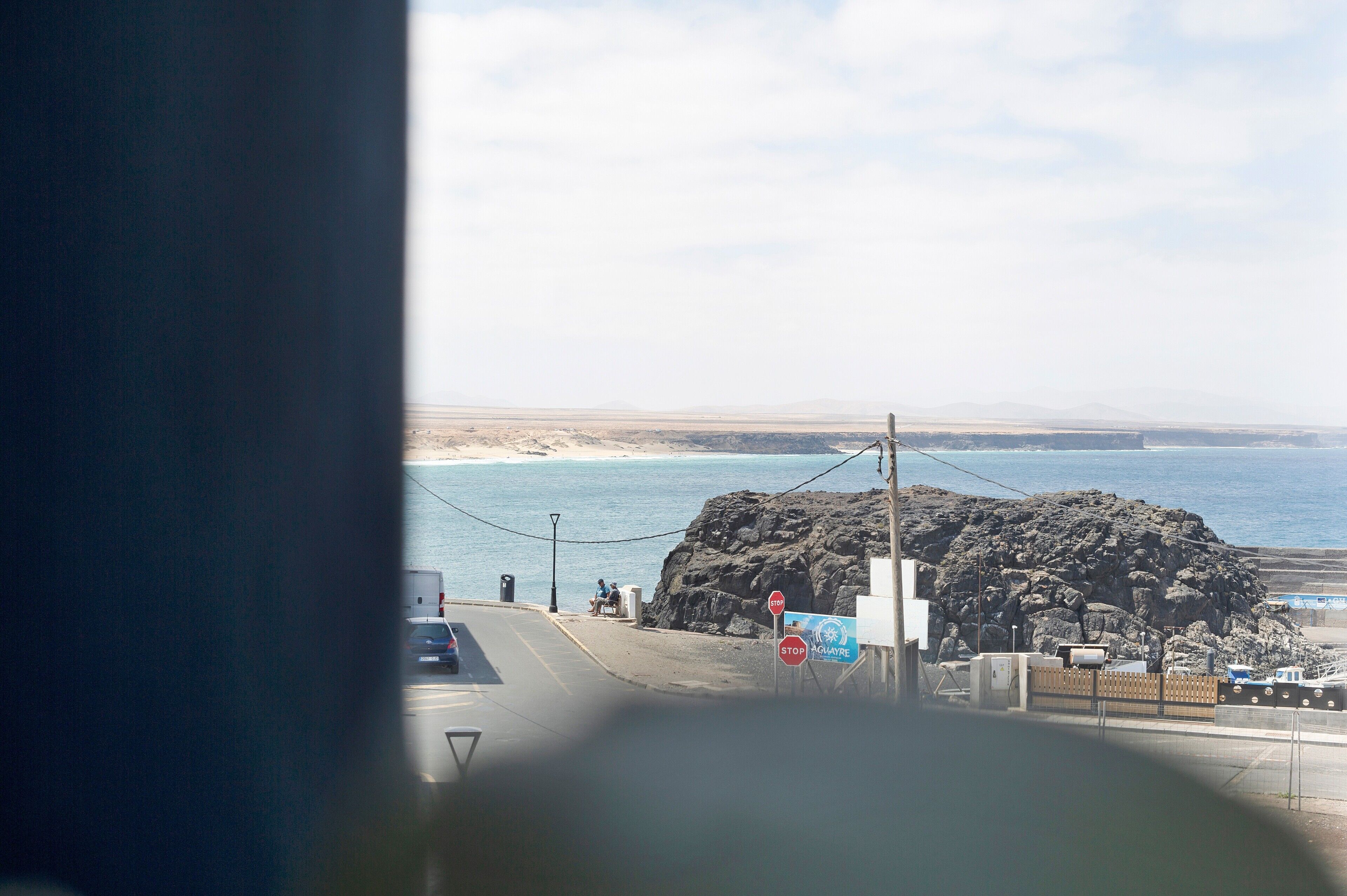 A coastal road with a stop sign, a rocky outcrop, and a view of the sea.