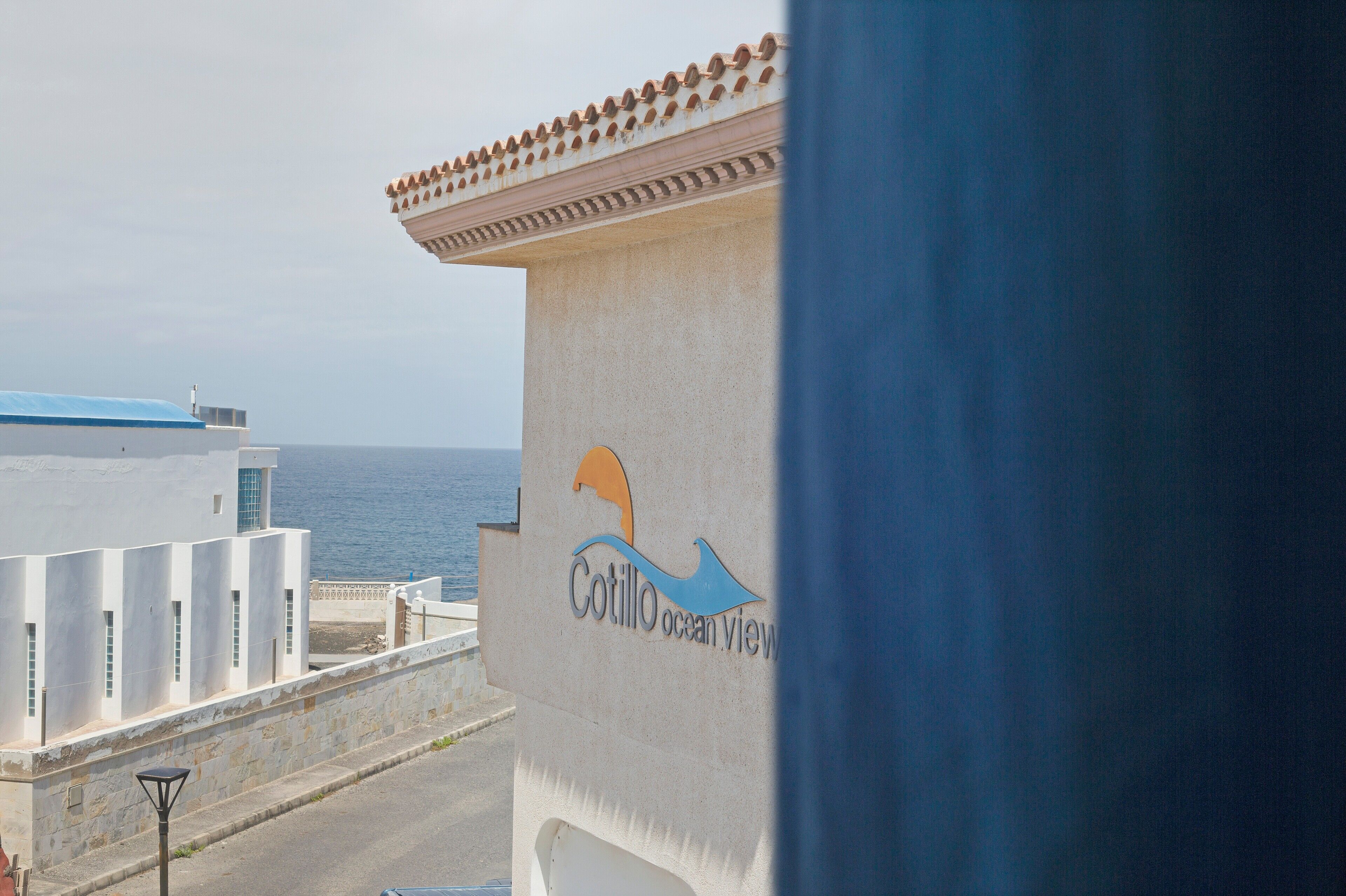 A building with a sign reading 'Cotillo Ocean View' and a view of the sea.