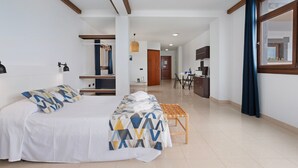 A hotel room with a bed, a bench, a desk, and a view of the kitchen. - Vacation Studio 'Estudio Vista Mar 5' with Sea View, Shared Pool and Wi-Fi (El Cotillo)