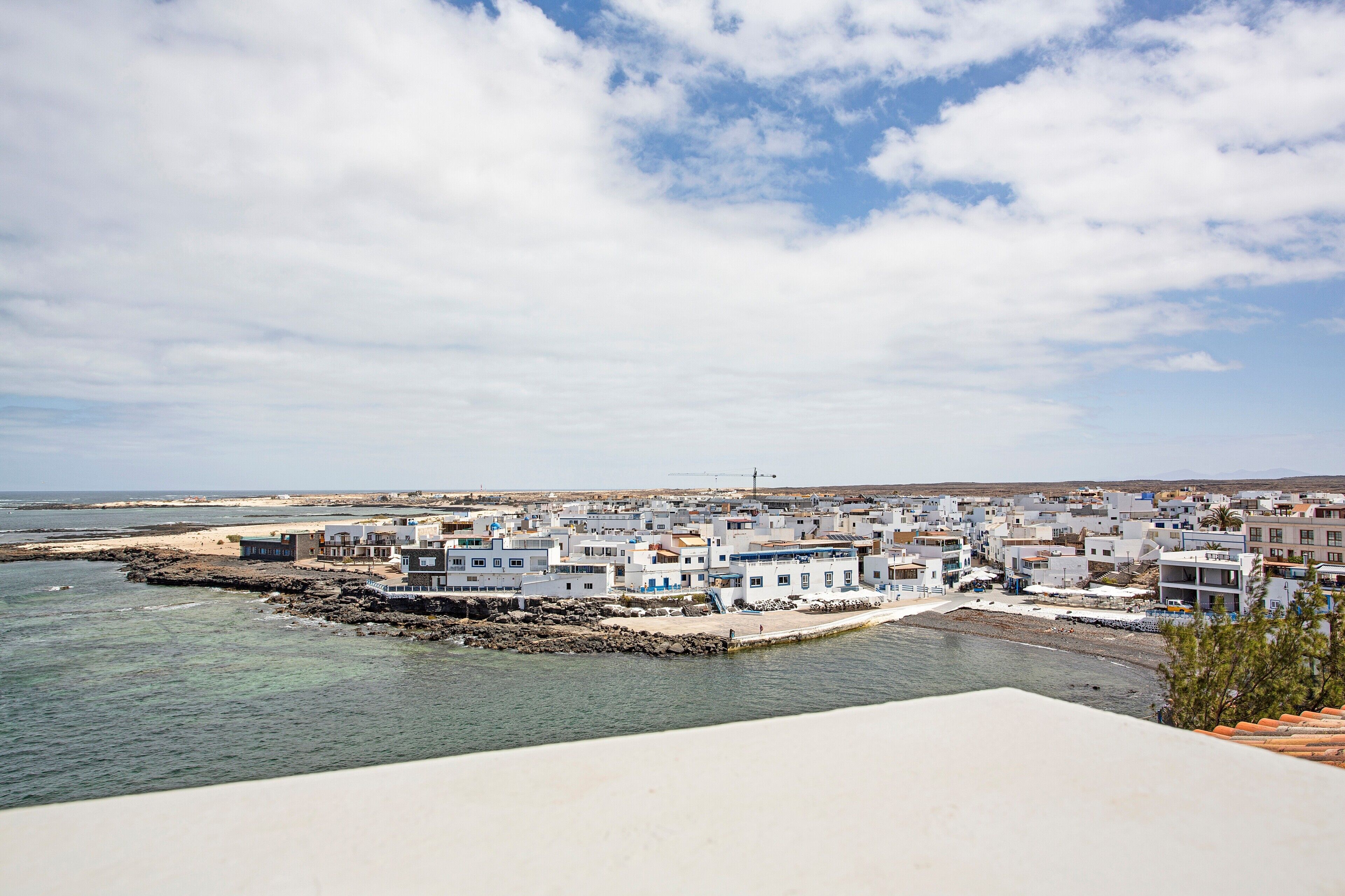 Une ville côtière avec des bâtiments situés près de l’eau, un ciel dégagé et une côte rocheuse.
