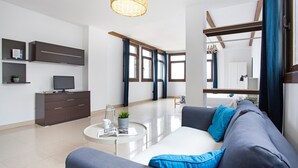 A modern living room with a sofa, coffee table, and a television on a cabinet. - Vacation Studio 'Estudio Vista Mar 5' with Sea View, Shared Pool and Wi-Fi (El Cotillo)