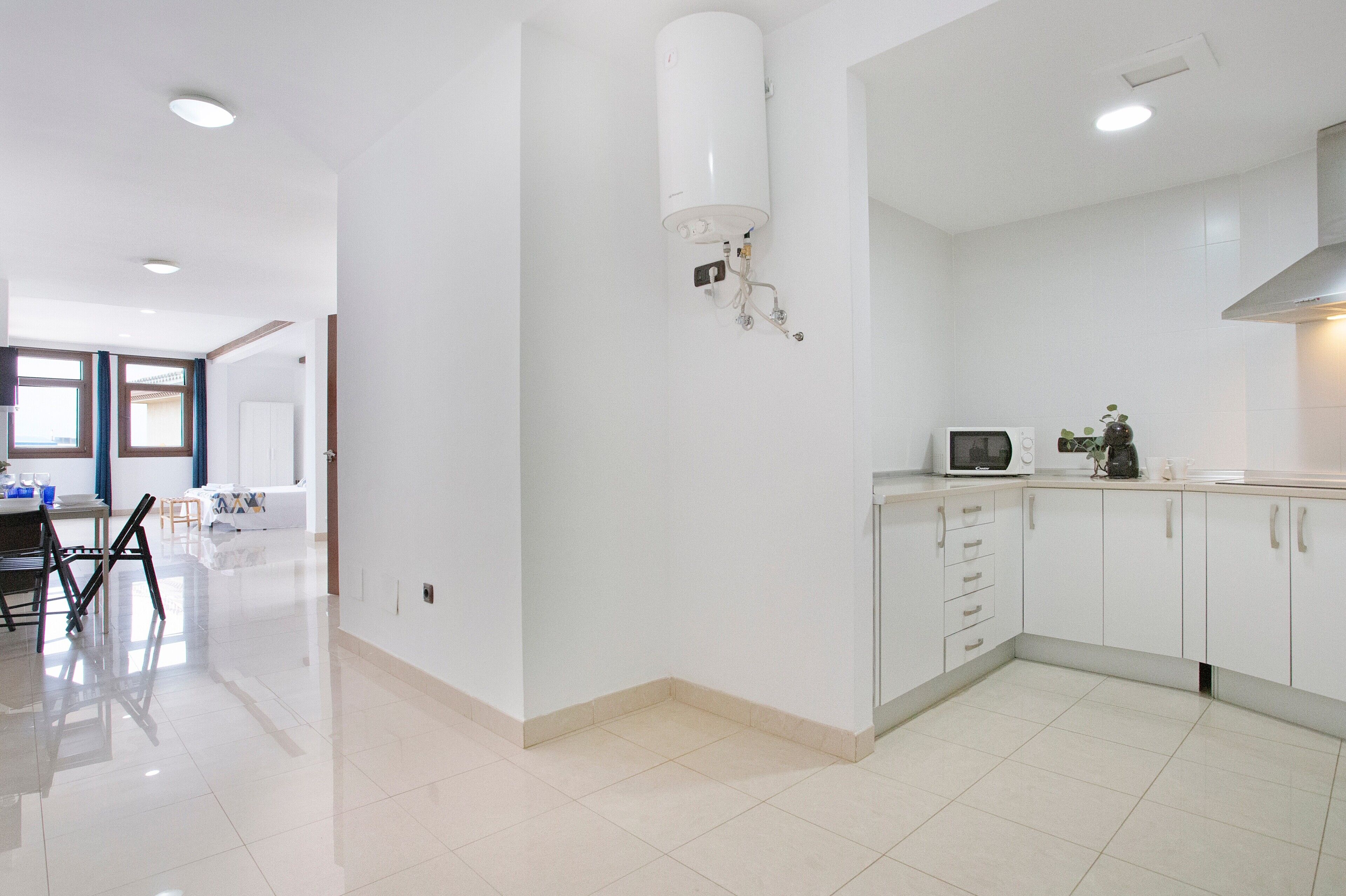 A modern kitchen with white cabinets, a microwave, and a water heater.