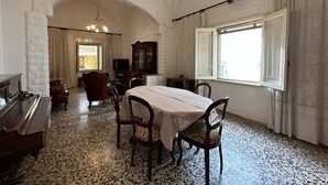 A dining room with a table set for four, a piano, and a television in the background.