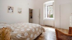 Ein Schlafzimmer mit einem Bett, einem Korbstuhl, einem Kleiderschrank und einem Fenster mit Blick.