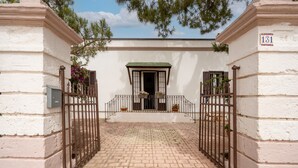 A white building with a number '131' on the right side, a gated entrance, and a small balcony with potted plants. - Stella — Apartment with Kitchen, Garden & Air Conditioning in Monopoli (Monopoli)