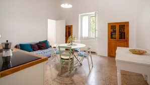 A compact living space with a kitchenette, a dining area, and a seating area with a sofa and chairs. - Stella — Apartment with Kitchen, Garden & Air Conditioning in Monopoli (Monopoli)
