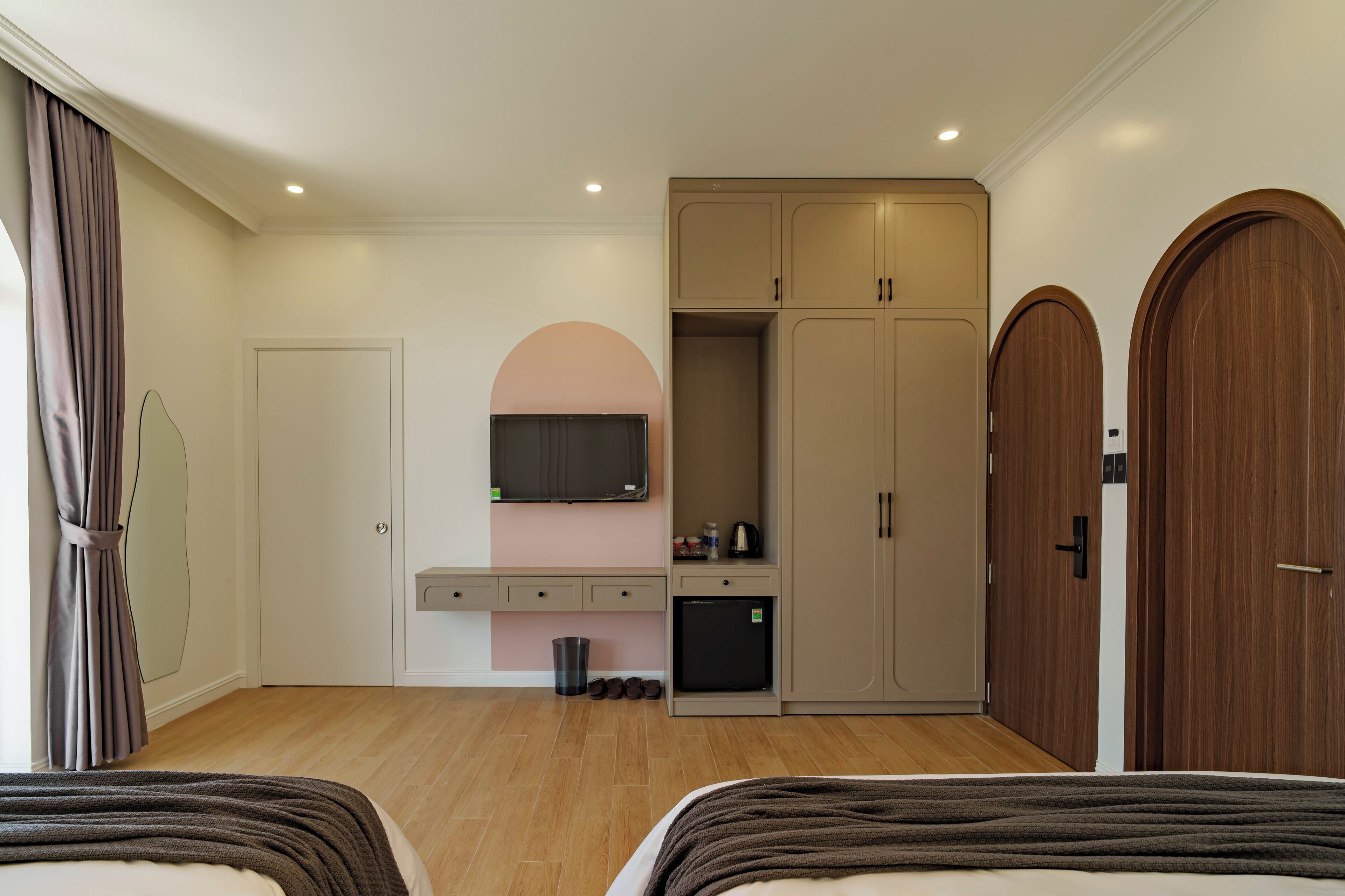 Un dormitorio moderno con cama, televisión, armario y una pequeña kitchenette.