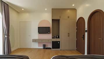 Un dormitorio moderno con cama, televisión, armario y una pequeña kitchenette.