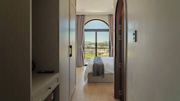 A bedroom with a large window, a bed, a bedside table, and a wardrobe.