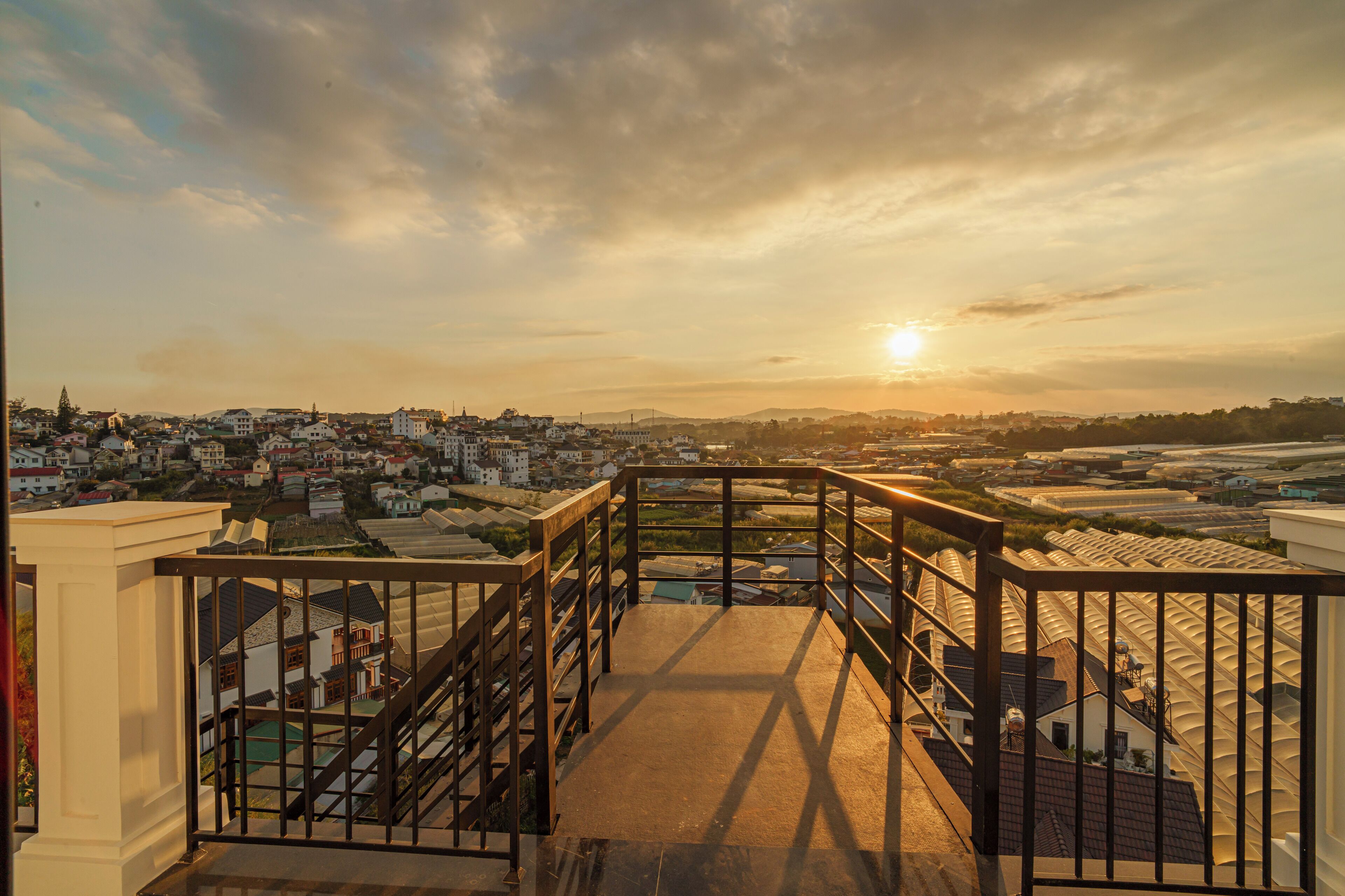 A staircase leading to a balcony overlooking a cityscape during sunset.