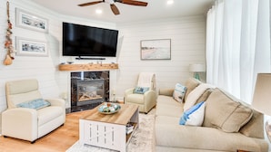Un salon avec une cheminée, un ventilateur de plafond, un téléviseur à écran plat et un canapé.