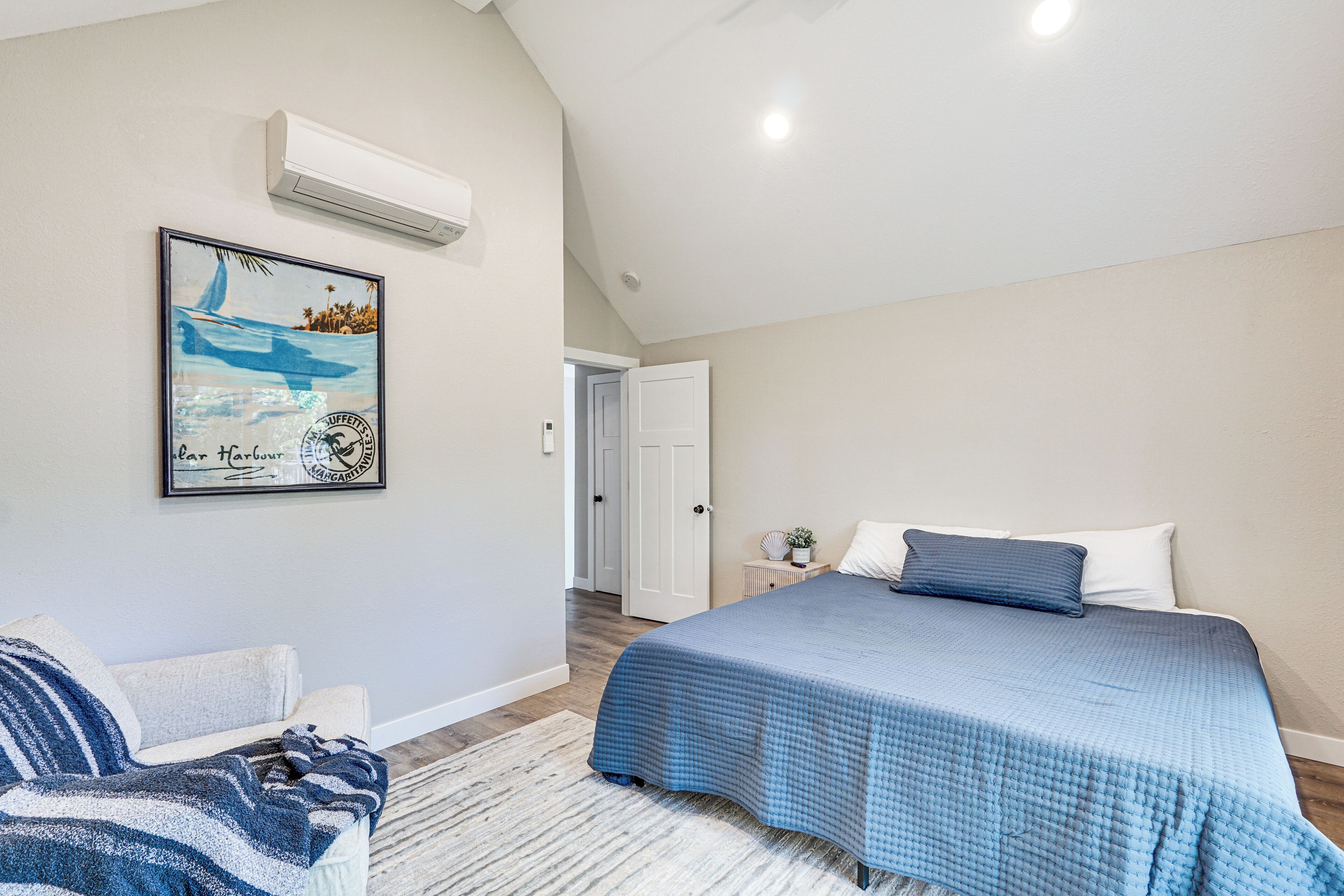 Une chambre à coucher comprenant un lit, une chaise, un tapis et un climatiseur fixé au mur.