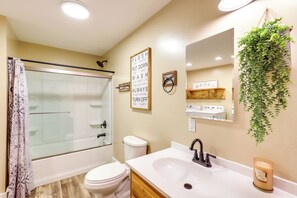 Ein Badezimmer mit Duschkabine, Toilette, Waschbecken und Spiegel.