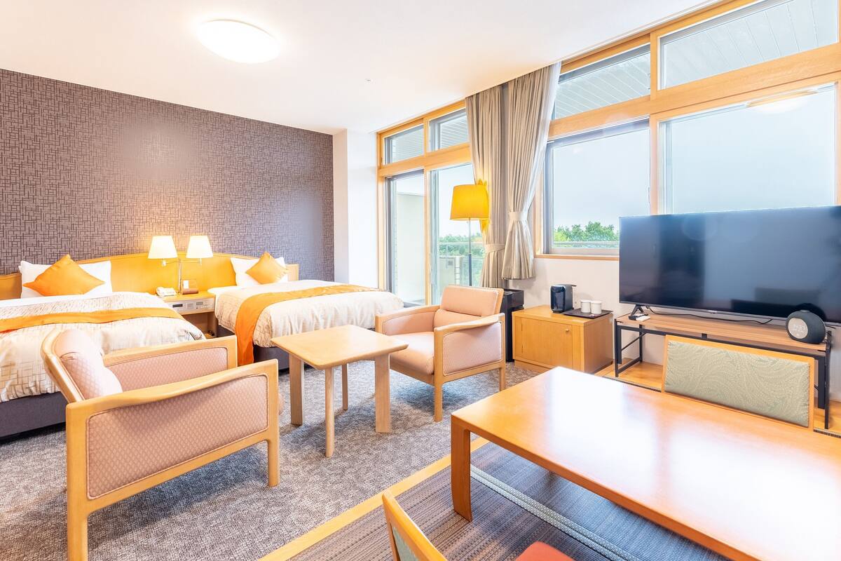 Een hotelkamer met een groot bed, twee nachtkastjes, een televisie, een bureau en een stoel.