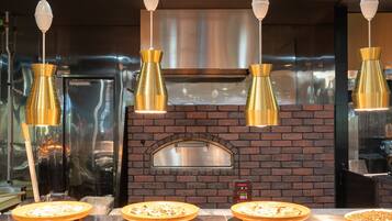 Un four à pizza équipé de quatre plaques à pizza, un mur en briques et des lampes suspendues.