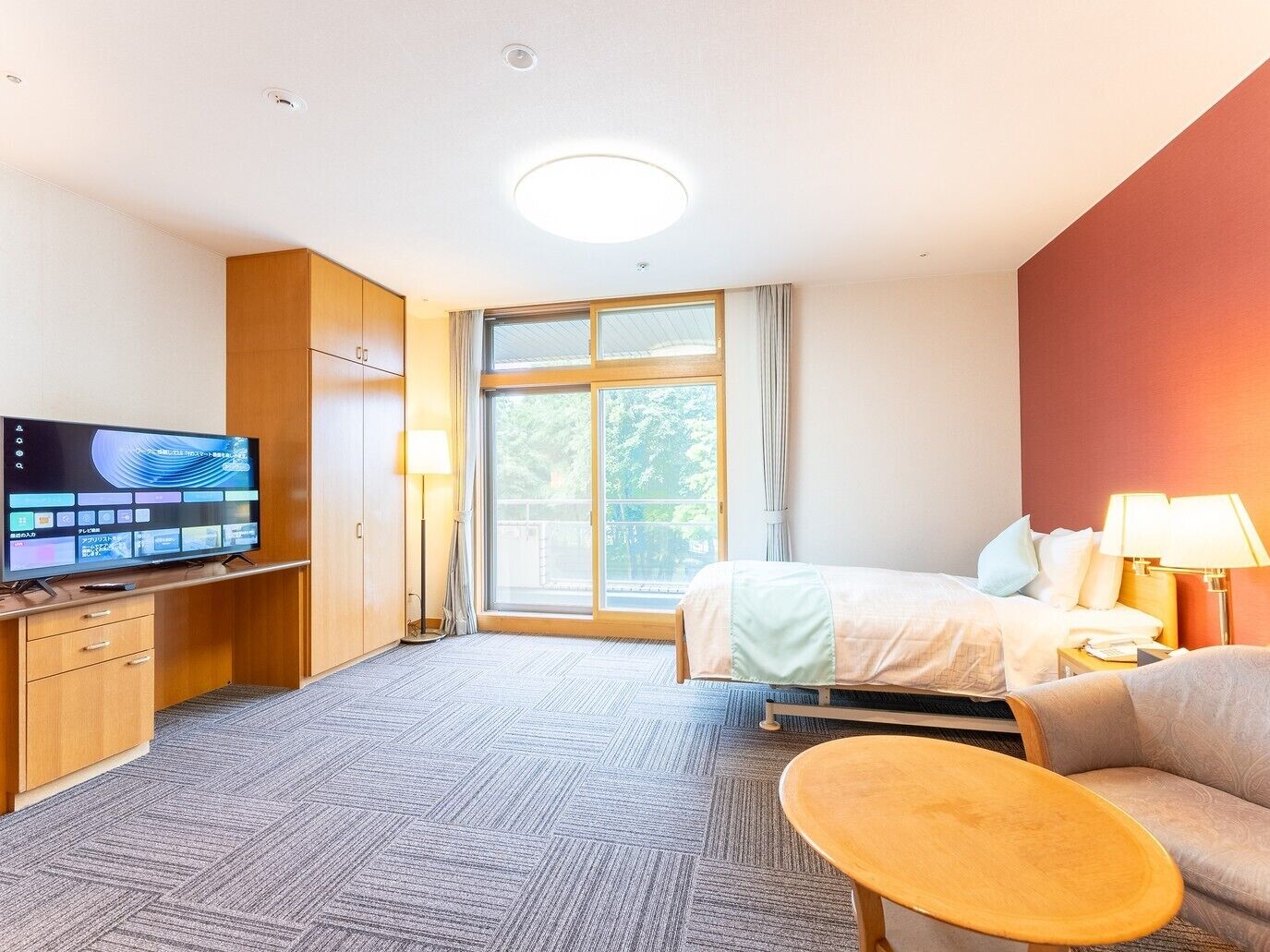 A hotel room with a bed, a TV, a desk, a chair, and a window.