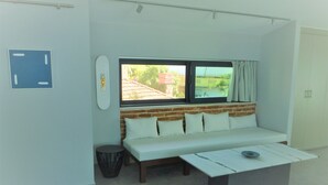 En moderne stue med en hvid sofa, et sofabord og et vindue med udsigt til en murstensbygning.