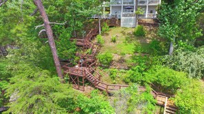 A wooden bridge connecting a building to a forested area.