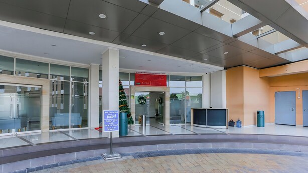 A modern building entrance with a glass facade, a no parking sign, and a Christmas tree. - Capital O 93931 Elzio Property (Depok)