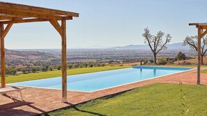 Une piscine rectangulaire agrémentée d’une pergola en bois d’un côté et d’une terrasse en briques de l’autre.