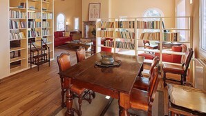 Une bibliothèque spacieuse avec des étagères en bois, une grande table à manger en bois et des fauteuils en cuir.