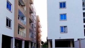 A swimming pool surrounded by multi-story buildings with balconies and windows. - Pavilion Suites Nyali (Mombasa)
