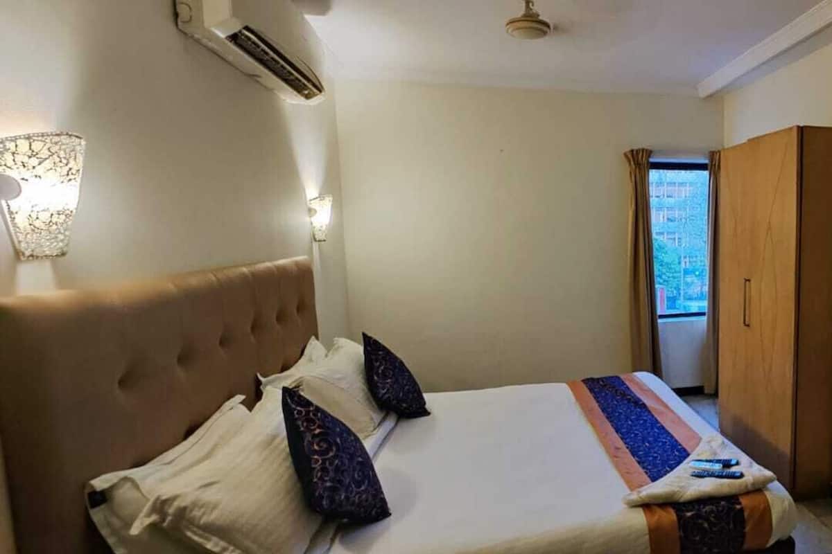 Ein Hotelzimmer mit einem Bett, einem Kleiderschrank, einem Fernseher und einem an der Wand befestigten Regal.