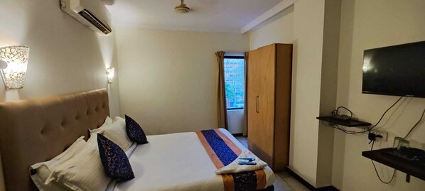 A hotel room with a bed, a wardrobe, a TV, and a wall-mounted shelf. - Stayz Inn Teynampet (Chennai)