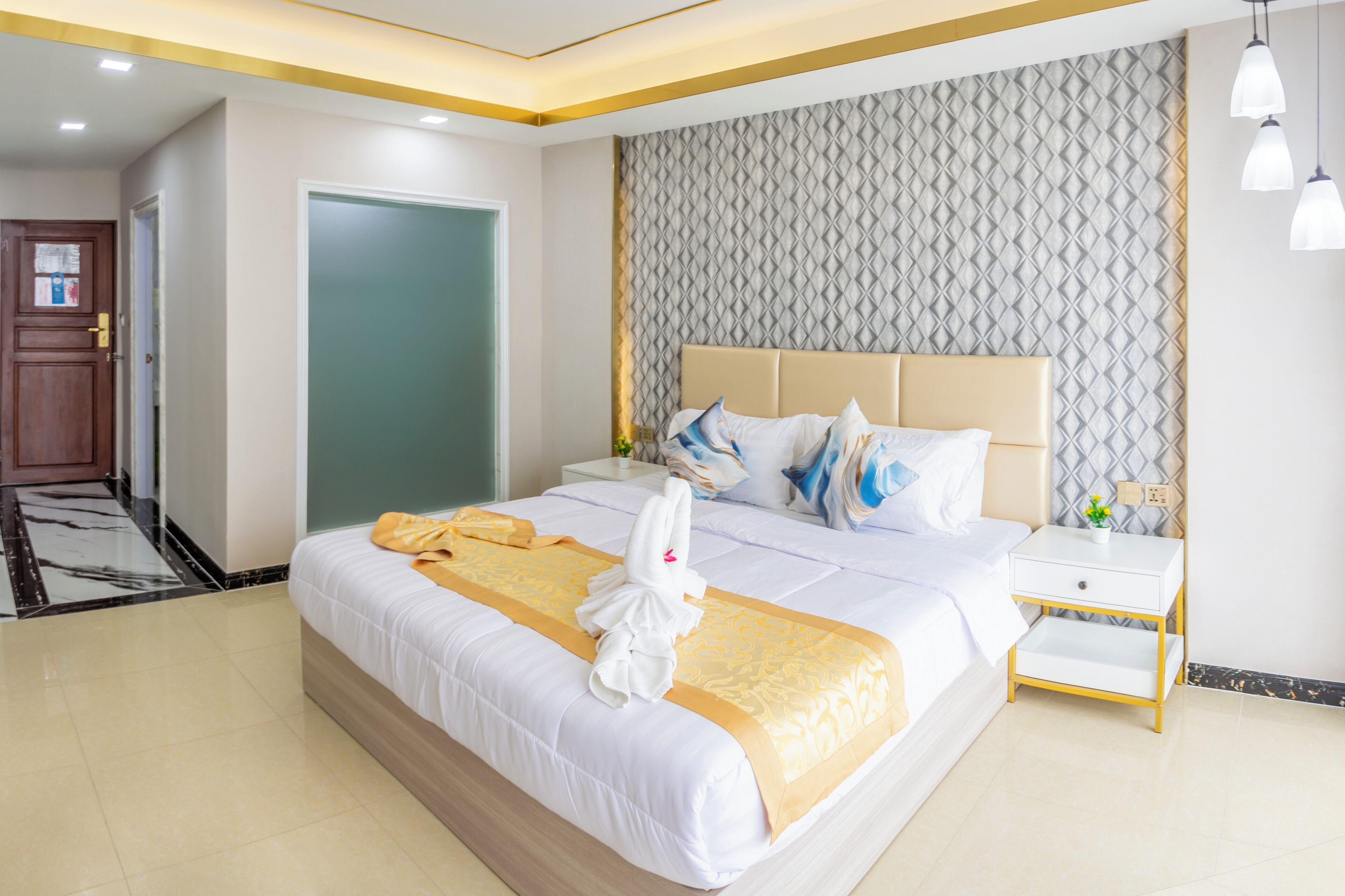 A hotel room with a bed, a nightstand, and a door.