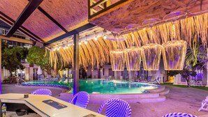 A pool area with lounge chairs, a bar, and a covered seating area with hanging lights. - Mermaid Beach Resort - 100m to Beach, Saltwater Pool & BeerGarden (Pattaya)