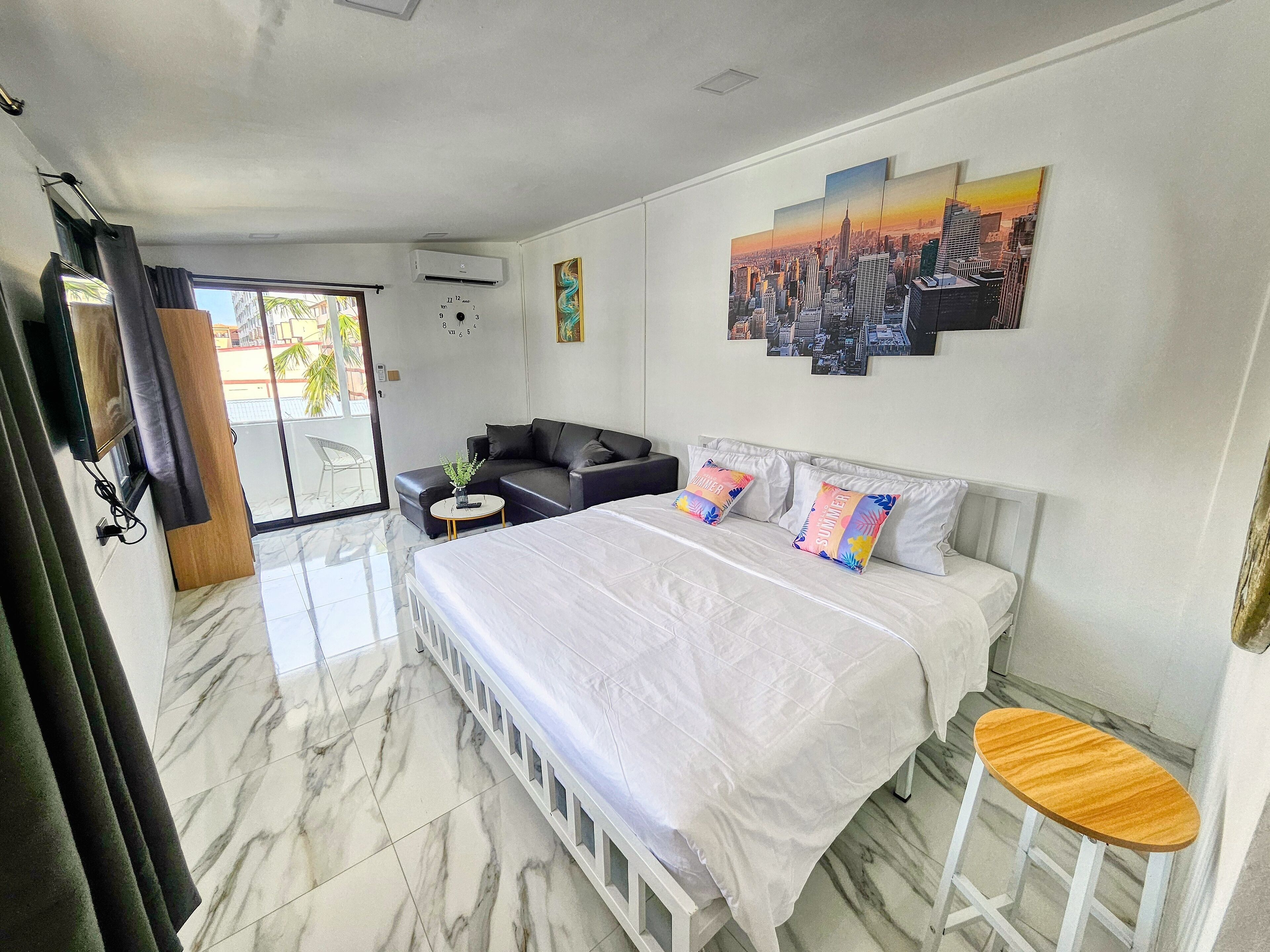 Ein modernes Hotelzimmer mit einem großen Bett, einer Couch, einem kleinen Tisch und einem Stadtbild an der Wand.