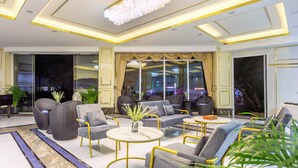 A modern lounge area with sofas, armchairs, and tables, featuring a large chandelier and large windows with curtains. - Mermaid Beach Resort - 100m to Beach, Saltwater Pool & BeerGarden (Pattaya)