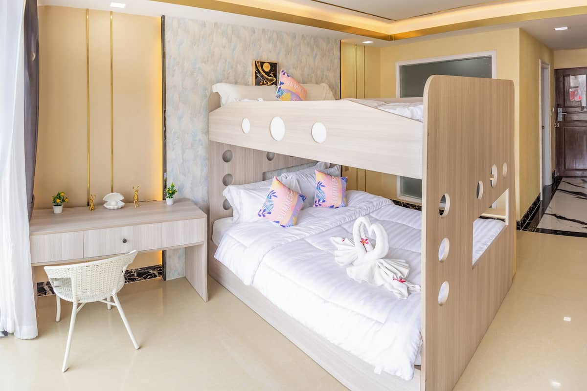 Une chambre avec un lit superposé, un bureau et une chaise, un tableau au mur et une décoration en forme de cygne sur le lit.