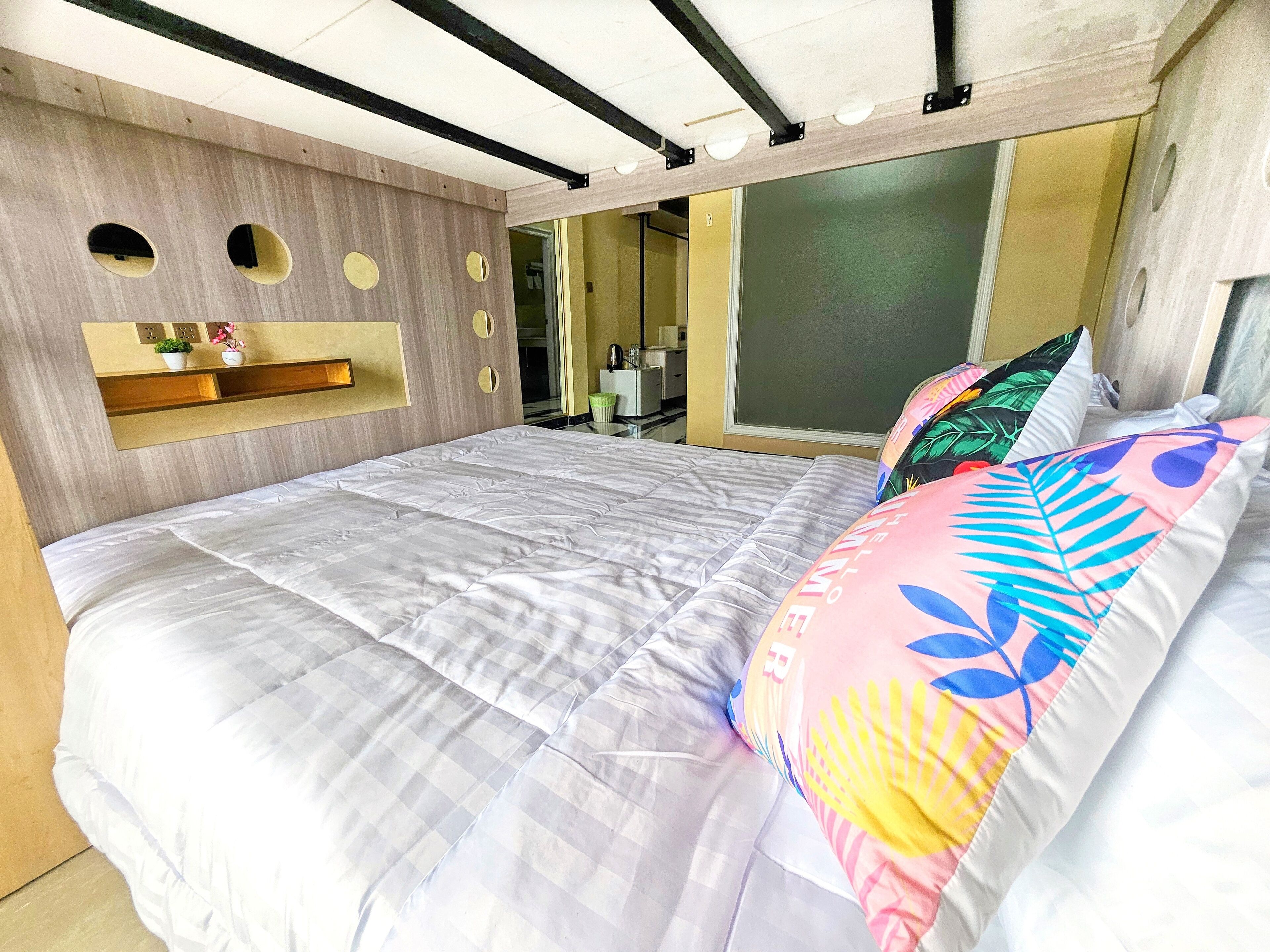 Une chambre moderne avec un grand lit, une étagère intégrée et un miroir.