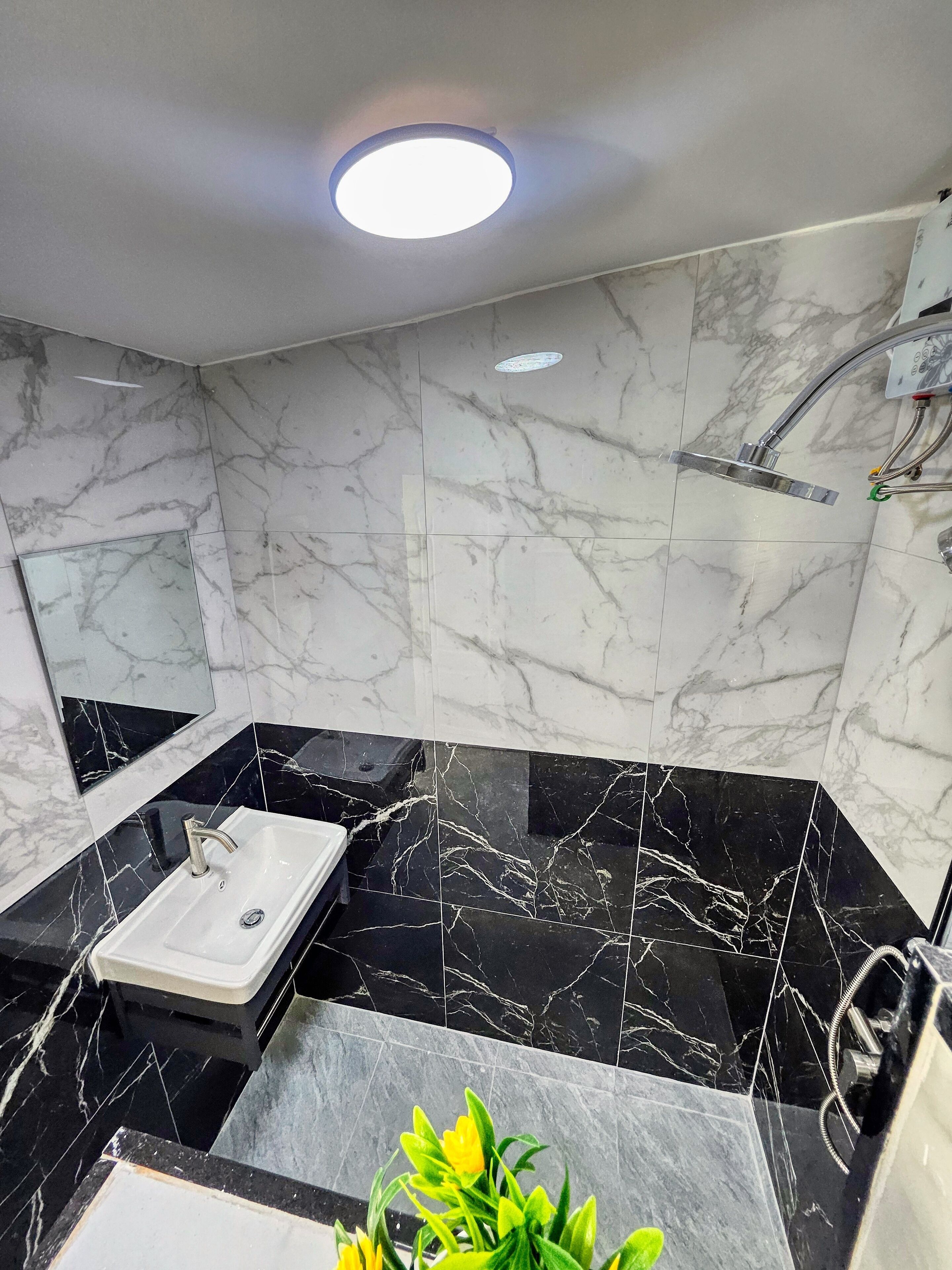Ein modernes Badezimmer mit einem weißen Waschbecken, schwarzen Marmorfliesen und einer Dusche.