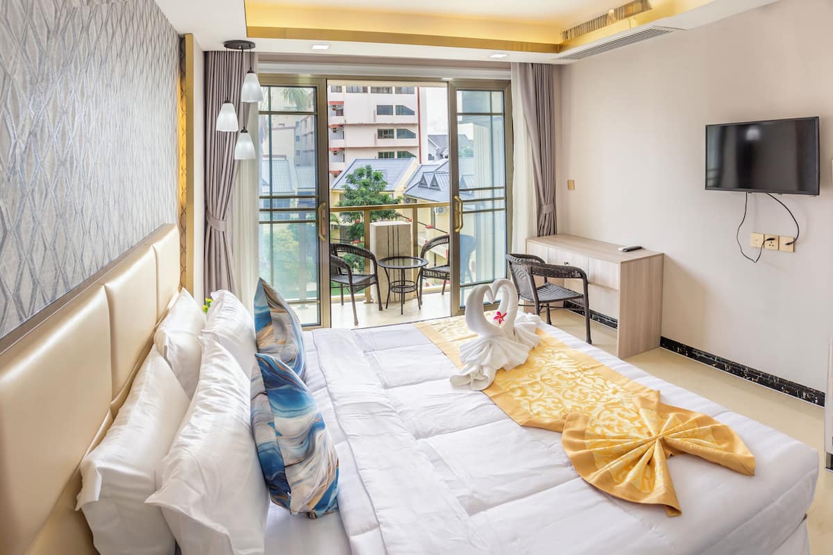 Une chambre d’hôtel équipée d’un lit, d’un bureau, d’une télévision et d’un balcon avec des chaises et une table.