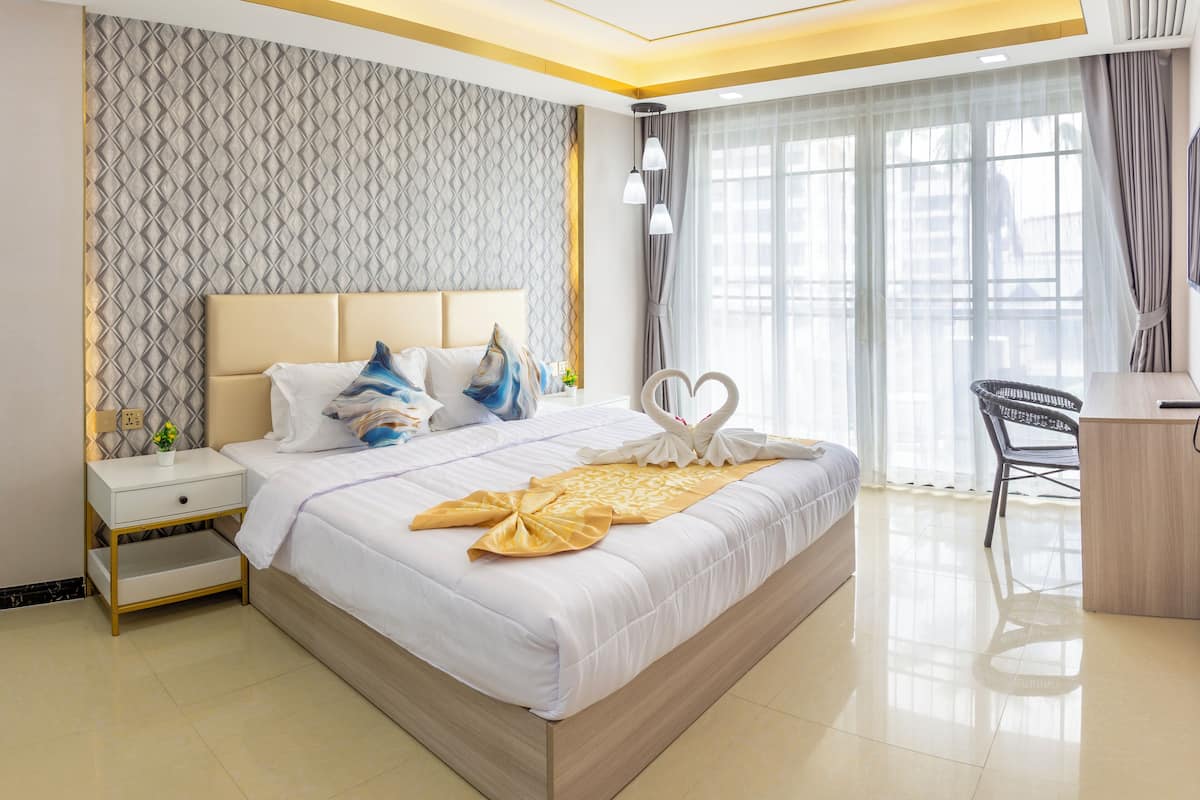 Une chambre d’hôtel avec un grand lit, une table de chevet, un bureau et une chaise.