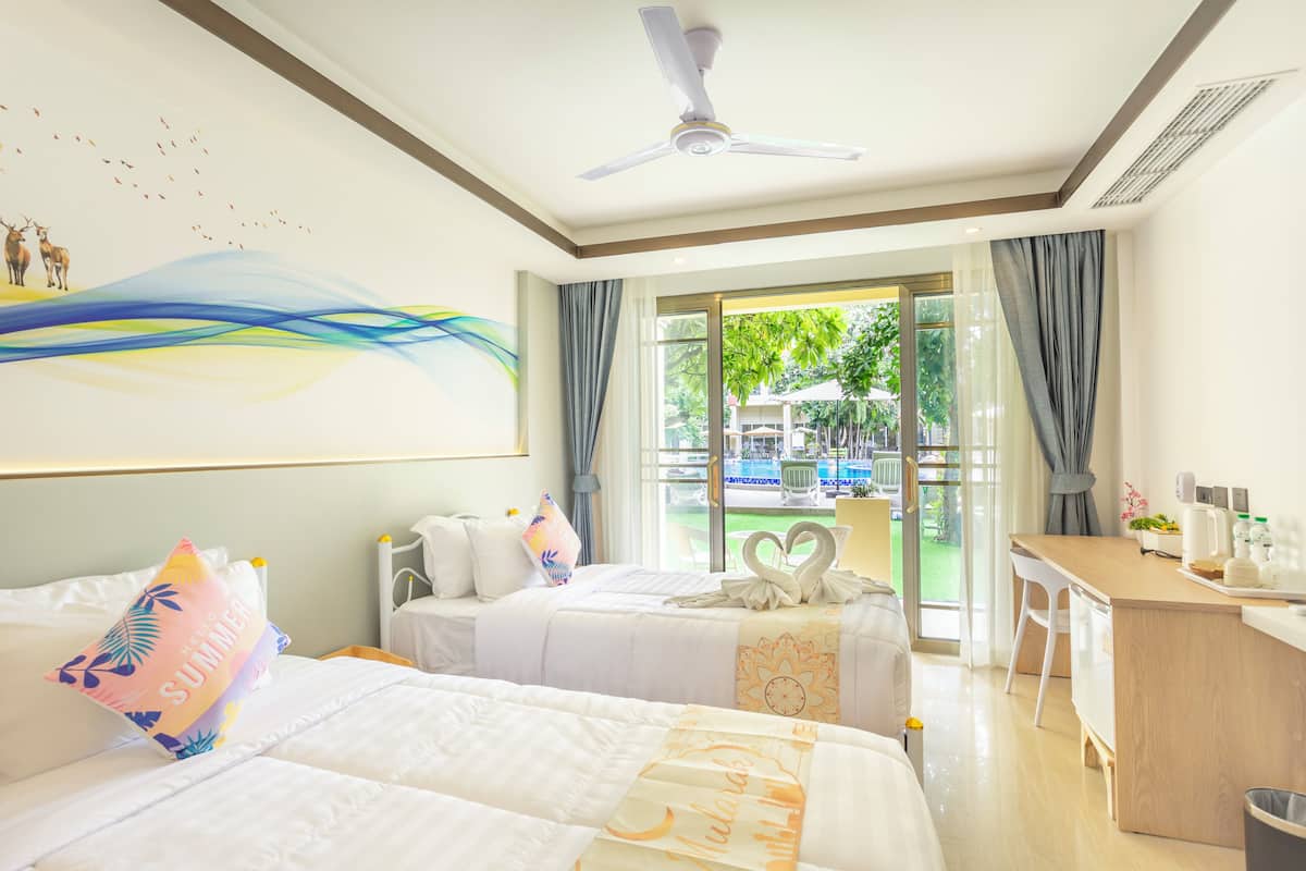 Une chambre d’hôtel avec deux lits, un bureau et une vue sur une piscine.