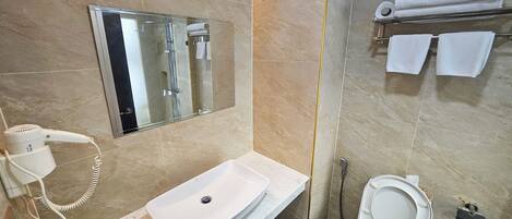 Une salle de bain équipée d’un lavabo, de toilettes et d’une douche à parois de verre.