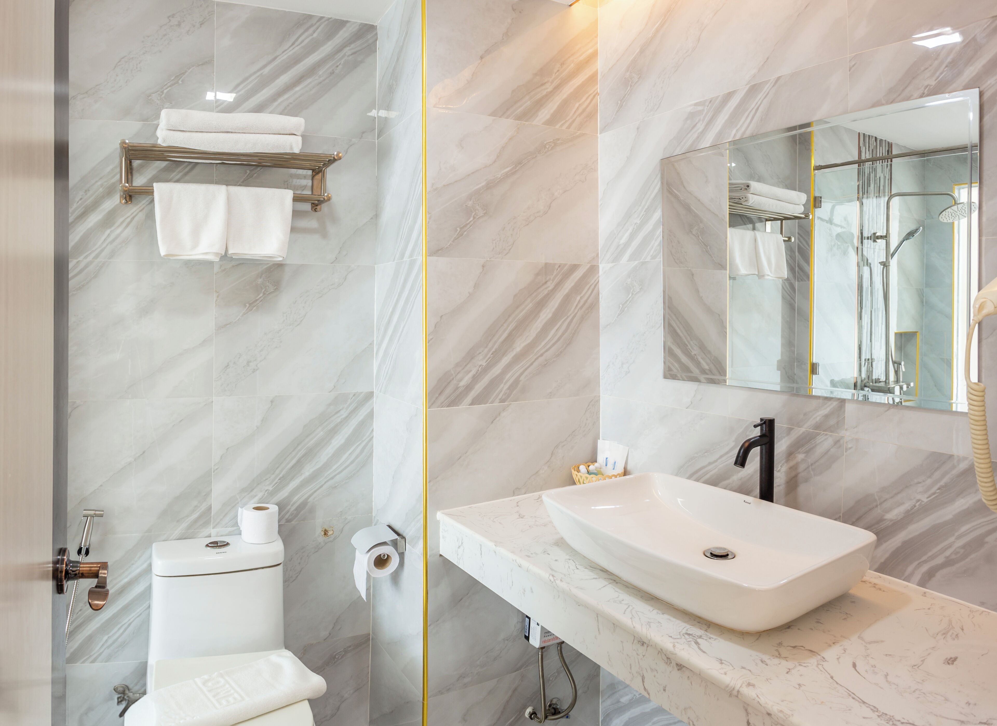 A modern bathroom with a marble floor, a white sink, a mirror, and a shower.