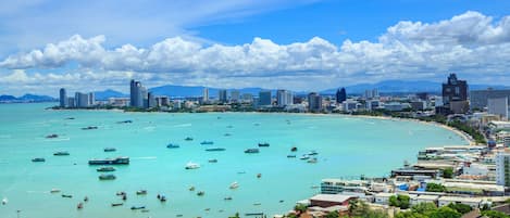 A coastal cityscape with a marina, buildings, and mountains in the background.