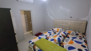 Een slaapkamer met een bed, een raam met een patroonverduistering, een airconditioning en een deur.
