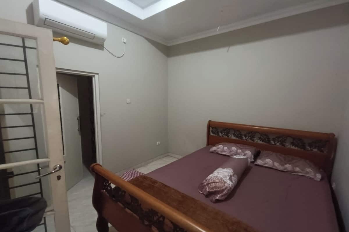 Ein Schlafzimmer mit einem hölzernen Bett, einer geschlossenen Tür und einer Klimaanlage an der Wand.