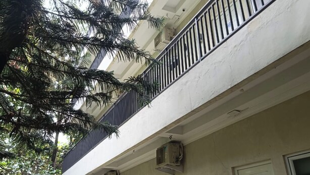 Een gebouw met een balkon, airconditioners en een deur met de aanduiding '102'.