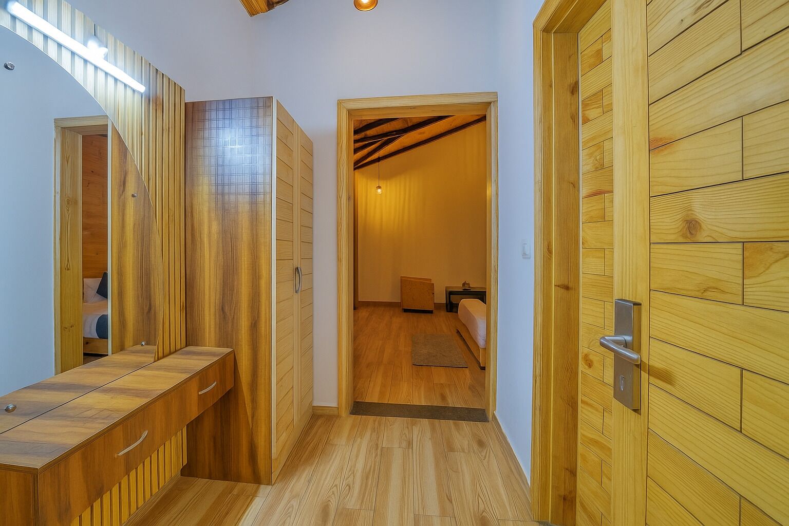 A hallway with wooden paneling, a bench, and a door leading to a bedroom with a bed and nightstand.