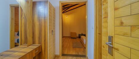 A hallway with wooden paneling, a bench, and a door leading to a bedroom with a bed and nightstand.
