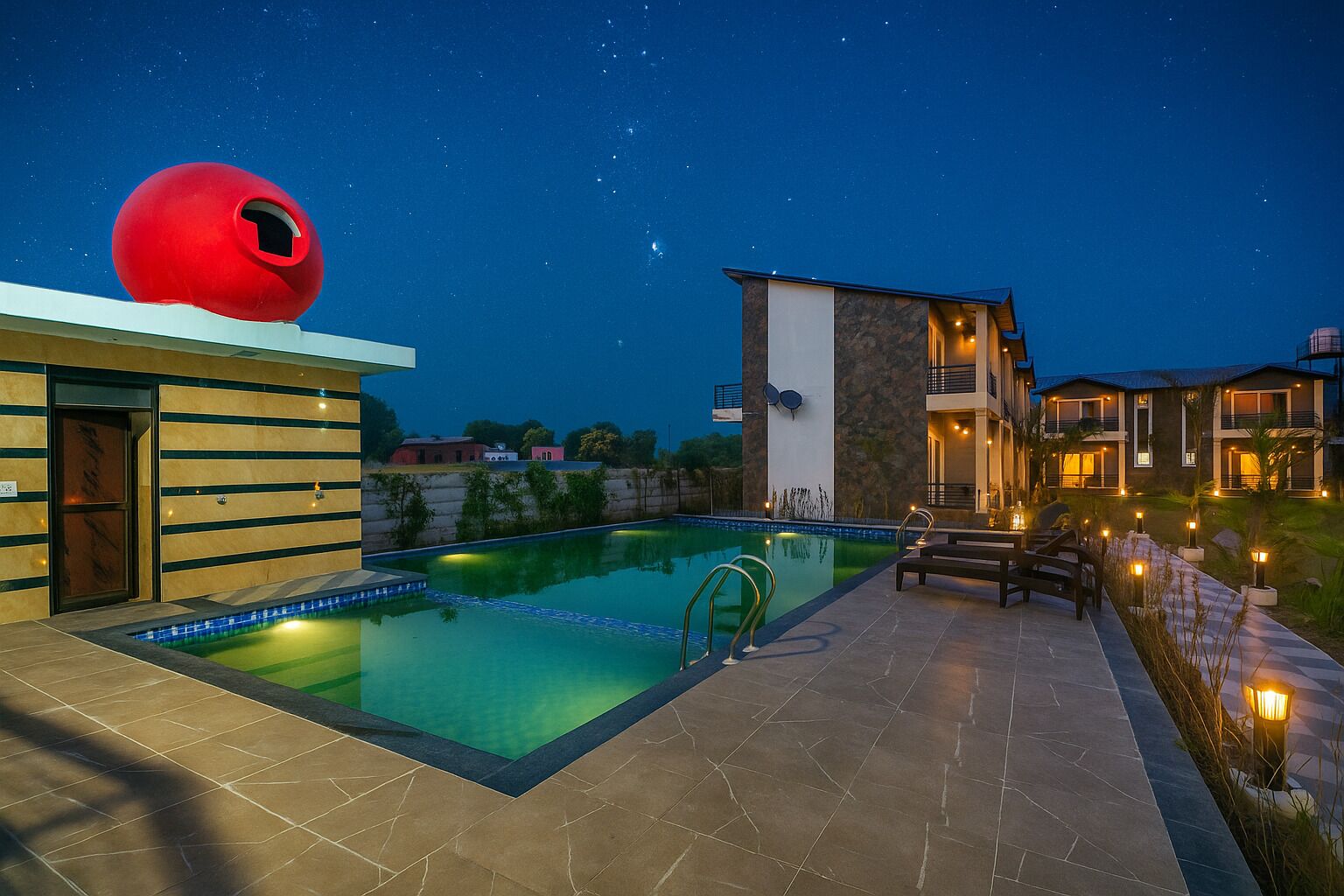 A swimming pool with a red spherical structure, a modern building with a stone facade, and a well-lit outdoor area with seating.